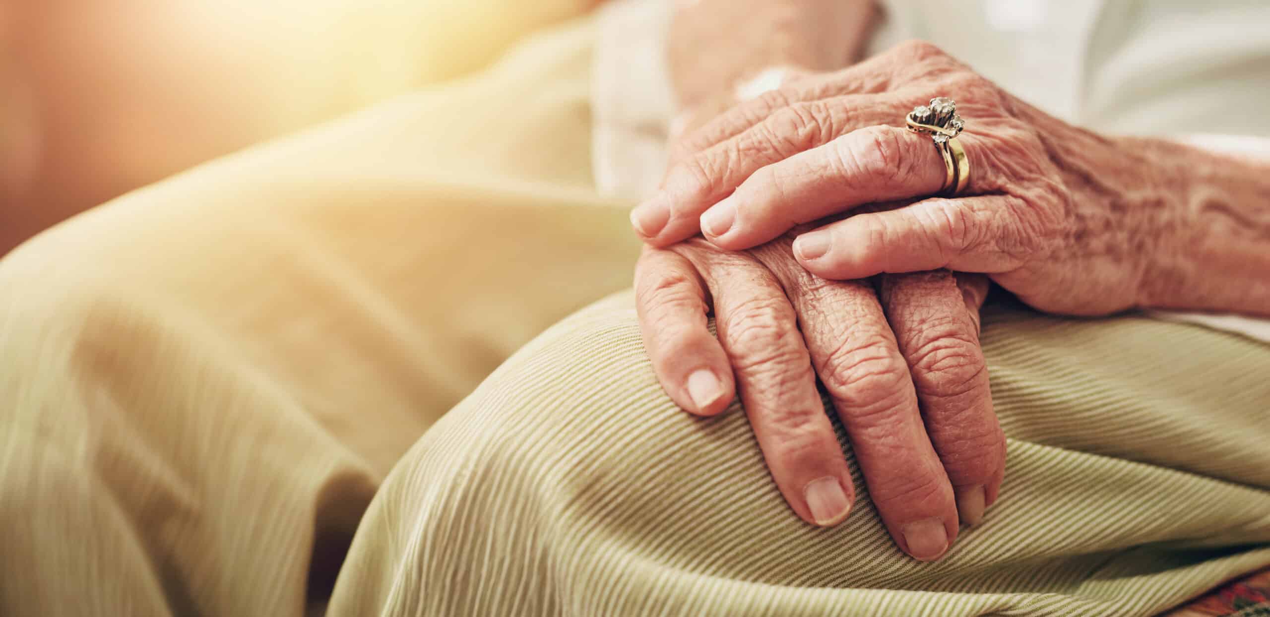 Gevouwen handen van een oudere vrouw in haar schoot